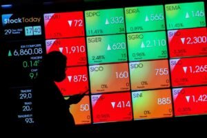 investor berjalan di depan papan digital IHSG - bursa saham