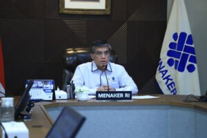 menaker duduk depan mic belakang bendera kemnaker